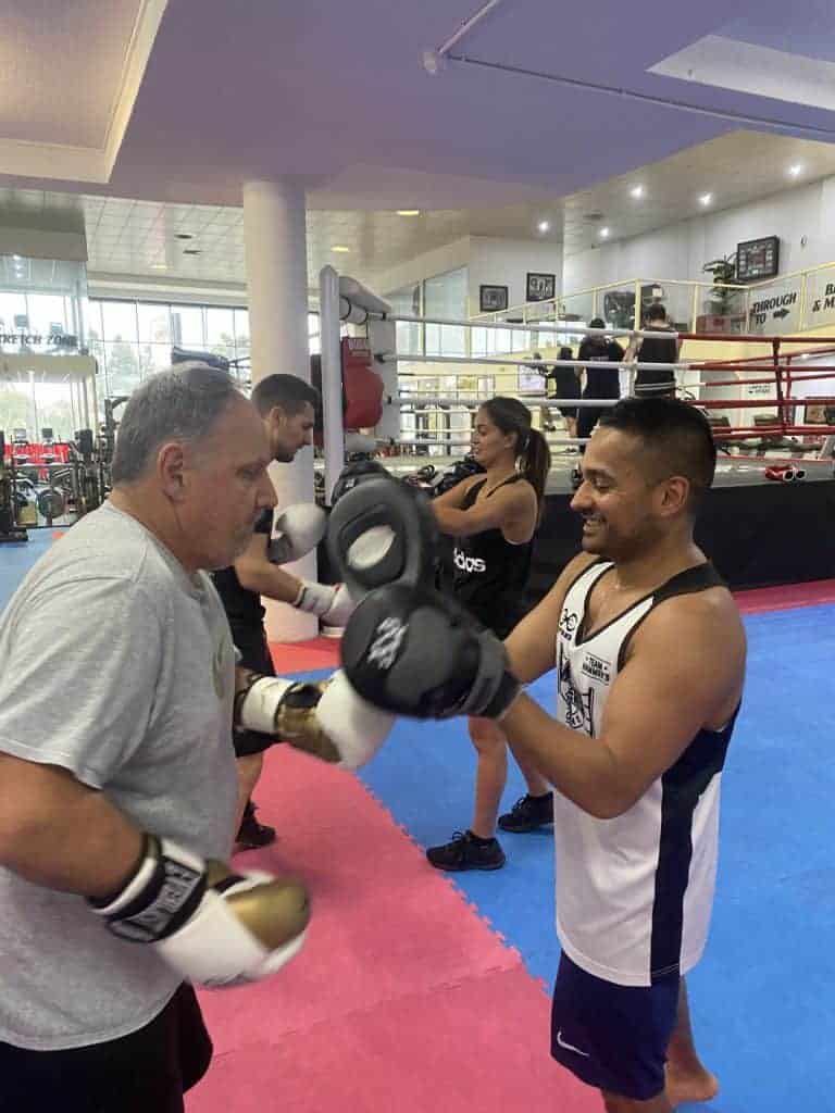 Coach holding focus pads for a boxer at Hammer's Gym Nunawading